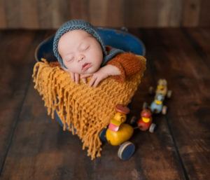 newborn baby sleeping in bucket with vintage wooden ducks