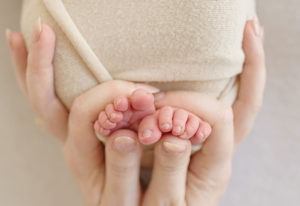 newborn baby toes with mothers fingers
