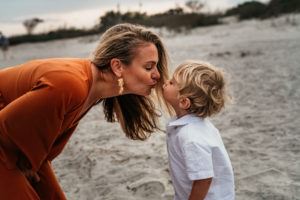 mother kissing her little boy on beach
