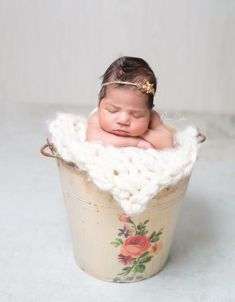 baby girl snuggled into a vintage pale with flowers