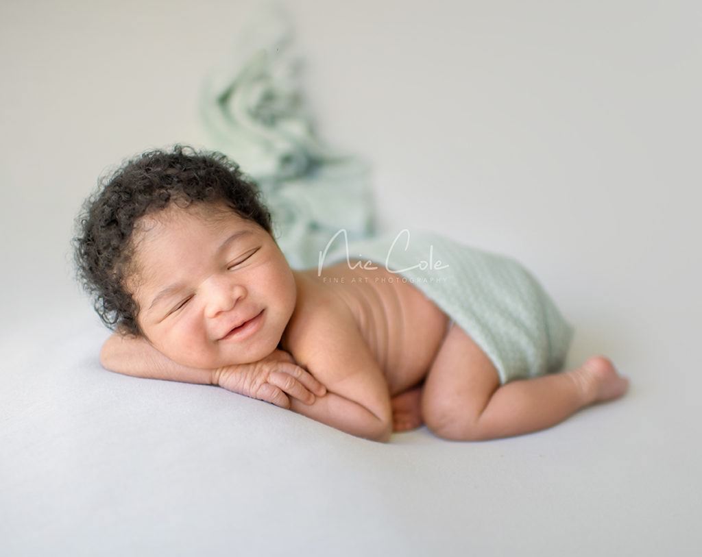 smiling newborn baby boy in green