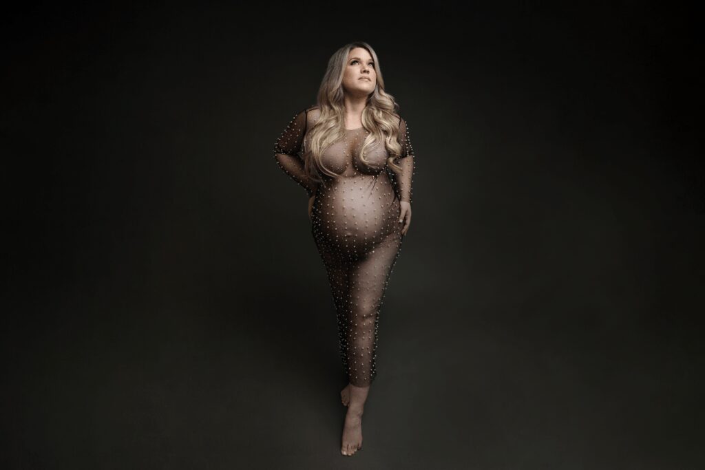 expecting mother on grey backdrop in Charlotte portrait studio wearing a sequin black maternity dress